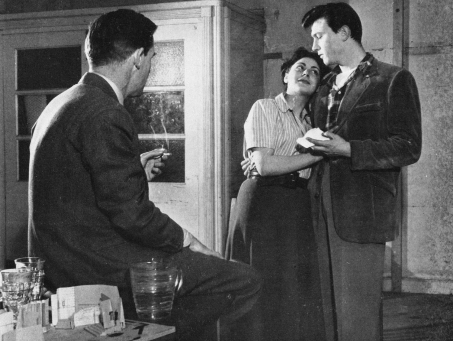 A man smoking a cigarette watches two actors rehearsing