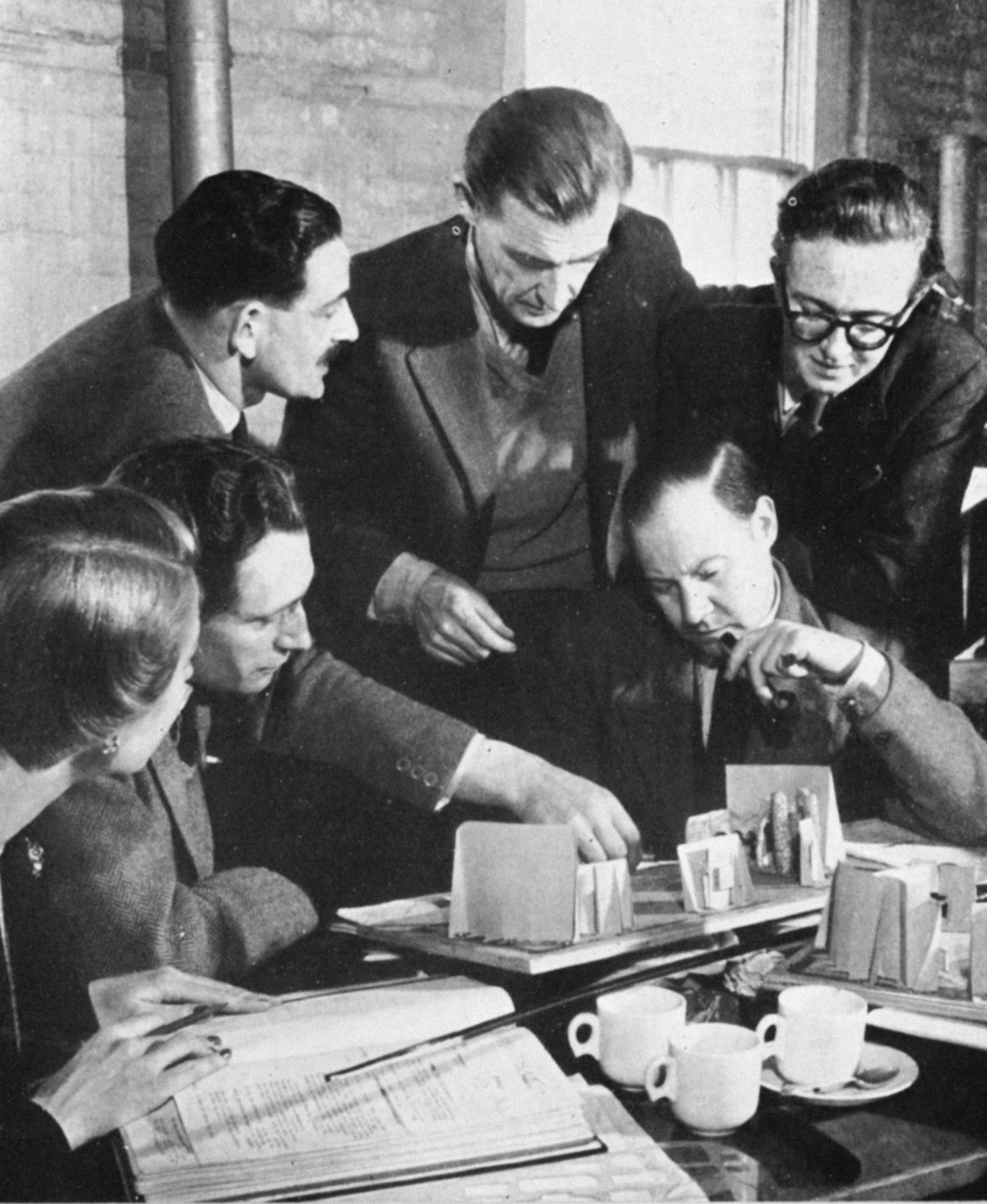 Men point at a model of the studio